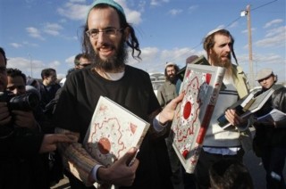 Israeli Orthodox Jewish men hold copies of the Quran, after Jewish settlers vandalized the local mosque