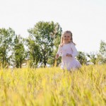 Little girl running through tall grass in meadow