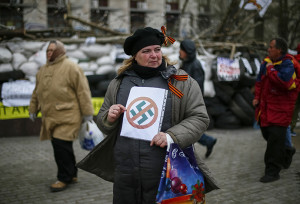 Protestor holding anti-swastika sign outside a regional government building -- you go, girl!