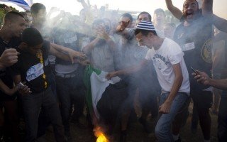 Settler protestors burning a Palestinian flag