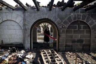 A nun surveys heavy damage at the Church of the Multiplication after a fire broke out in the middle of the night near the Sea of Galilee in Tabgha, Israel, Thursday, June 18, 2015. Israel police spokesman Micky Rosenfeld said police are investigating whether the fire was deliberate and are searching for suspects. A passage from a Jewish prayer, calling for the wiping out of idol worship, was found scrawled in red spray paint on a wall outside the church