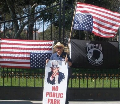 American Legionnaire Rees Lloyd holding a flipped American Flag in protest  of the VA’s misappropriation of land and the mistreatment of homeless Veterans 