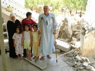 A Palestinian family standing in the ruins of their house in the West Bank which Israeli forces have just demolished in July 2005